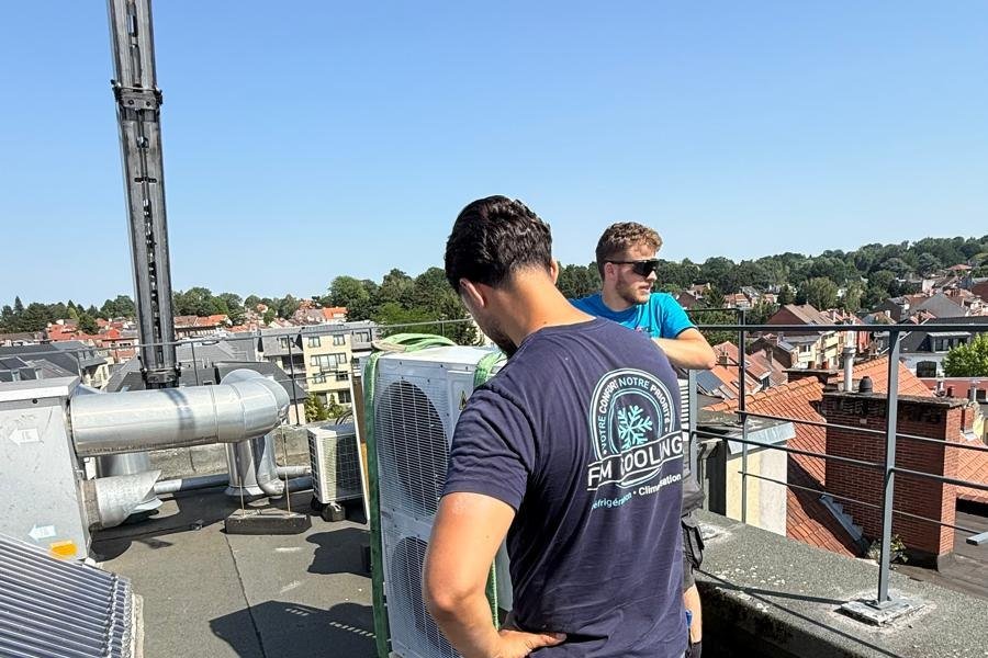 Techniciens FM Cooling manutentionnant une unité de climatisation en toiture à l'aide d'une grue